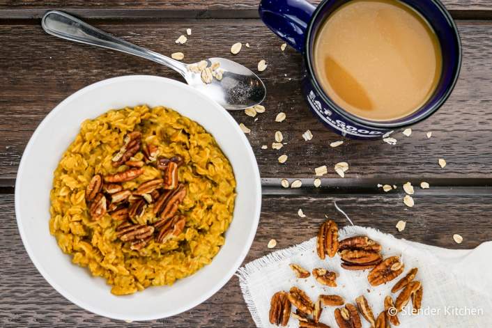 Pumpkin Pie Oatmeal with a spoon, loose oats, and pecans along with coffee.