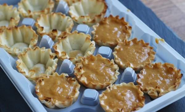 Mini Pumpkin Pies in a baking dish and filled with pumpkin before cooking.