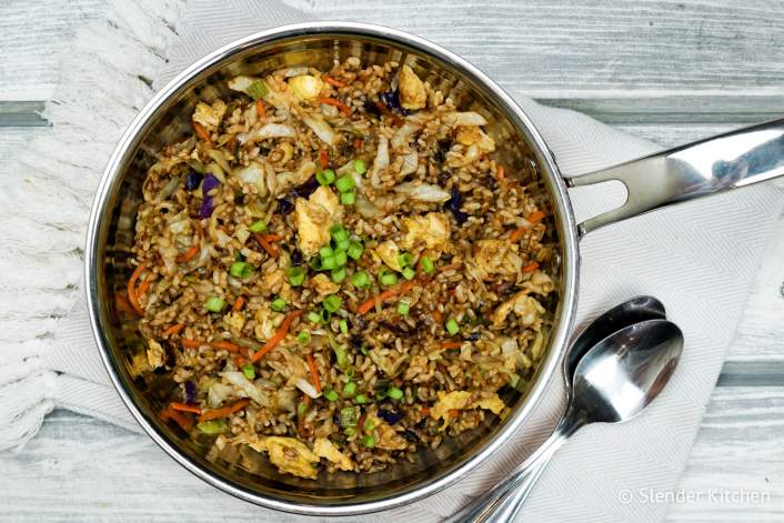 Healthy fried rice in a skillet with fresh scallions.