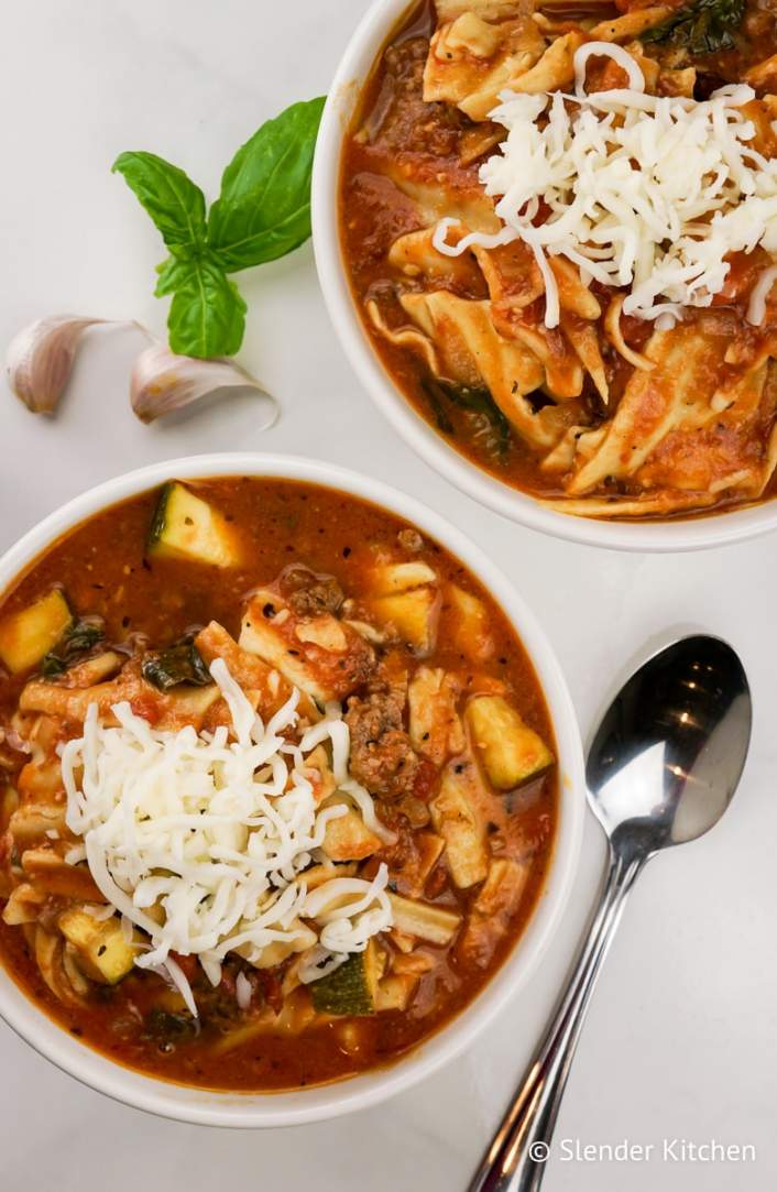Healthy Slow Cooker Lasagna Soup in a bowl with fresh basil and mozzarella cheese.