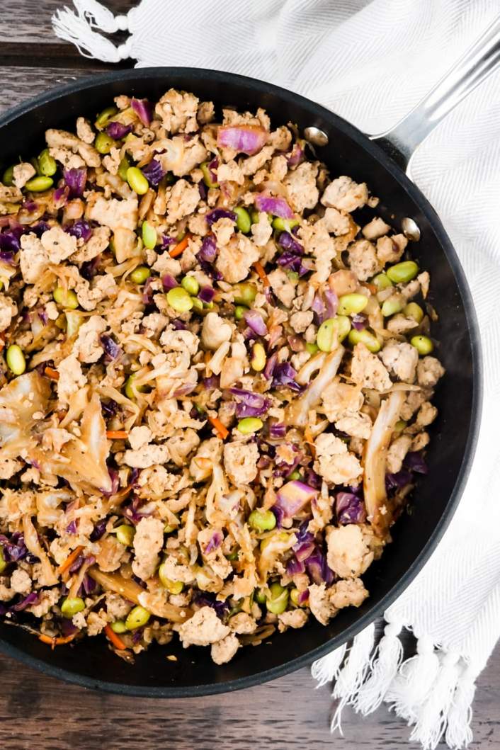 Egg Roll Bowls in a skillet served with rice and hot sauce.