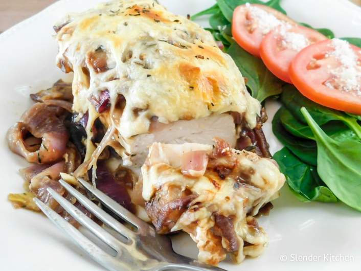French Onion Soup Chicken on a plate with lettuce and tomato salad.