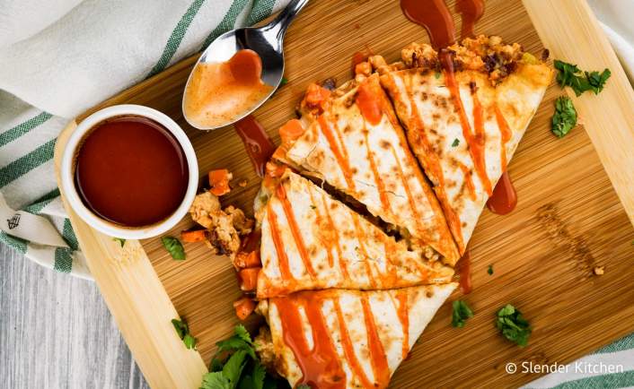 Healthy Buffalo Chicken Quesadilla cut into four pieces with extra sauce.
