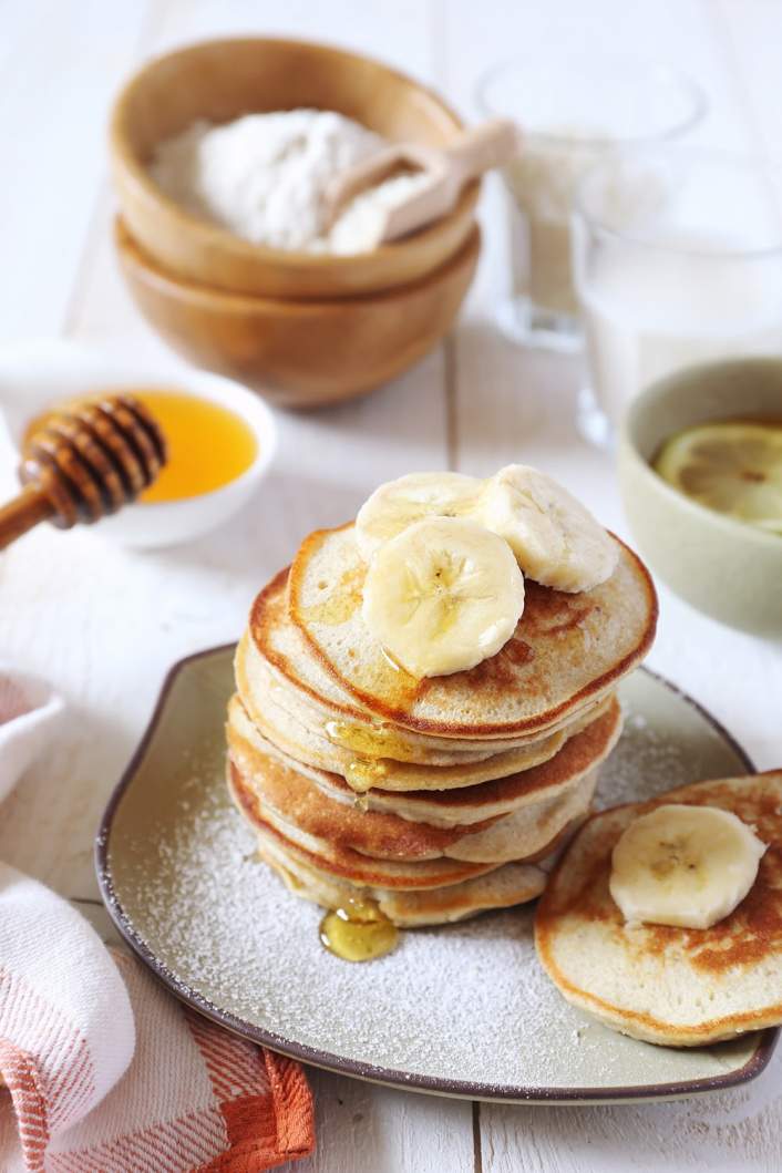 Three Ingredient Banana and Egg Pancakes stacked on a plate with bananas and strawberries