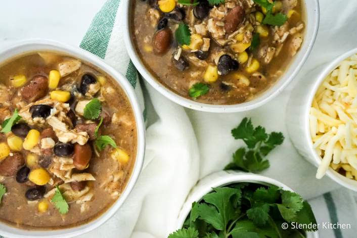 Slow Cooker Weight Watchers Taco Soup with cilantro, cheese, and baked tortilla chips.