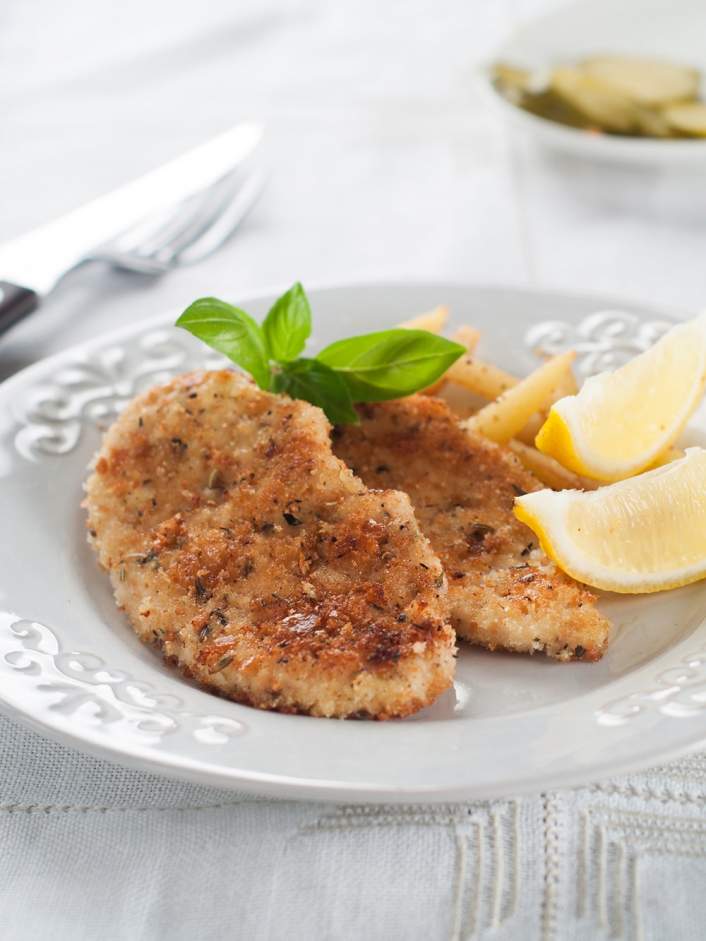 Weight Watchers Crispy Baked Pork with lemon wedges on a white plate.