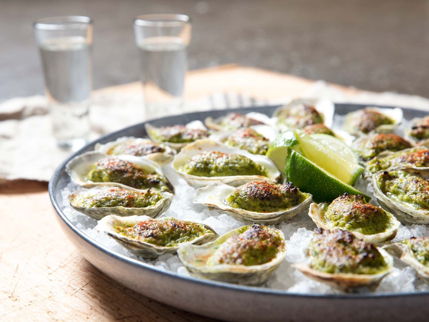 Side view of platter of oysters Oaxacafeller with glasses of mezcal.