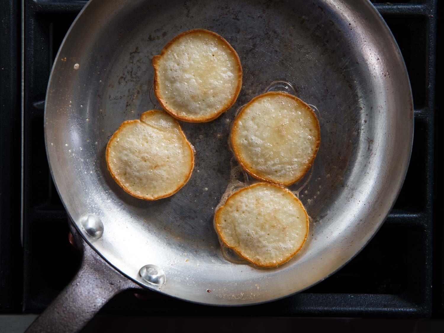 Blini cooking in a copper skillet, showing even browning