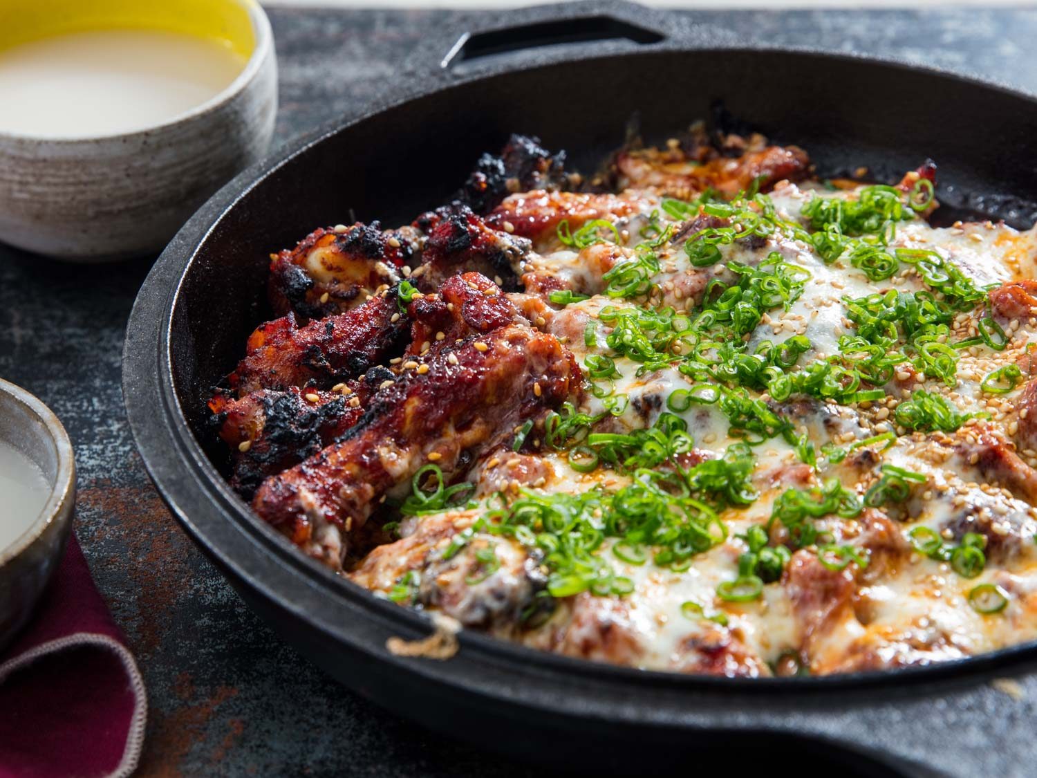 Side view of fire chicken with cheese, with bowl of makgeolli