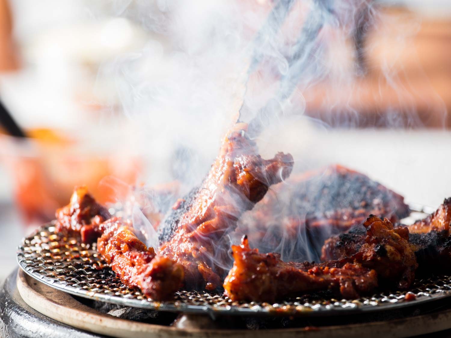 Closeup of turning pieces of chicken on the grill