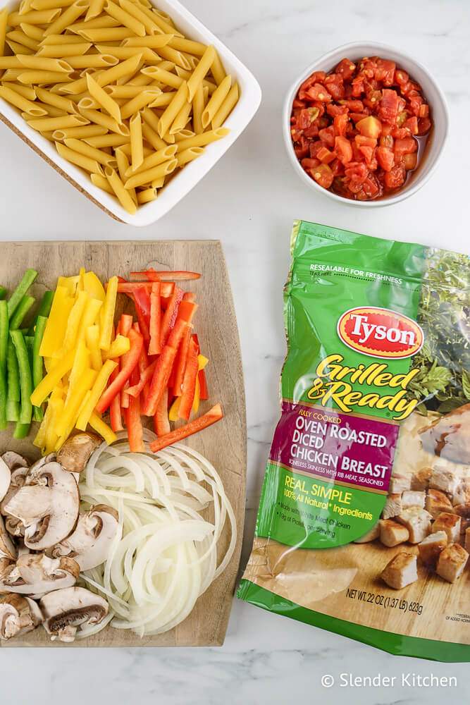 Ingredients for Chicken Fajita Pasta including dry pasta, peppers, onions, mushrooms, and tomatoes.