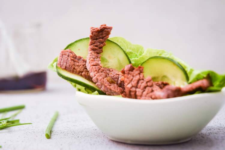 Korean lettuce wrap with beef, cucumbers, and onions in a small white bowl.