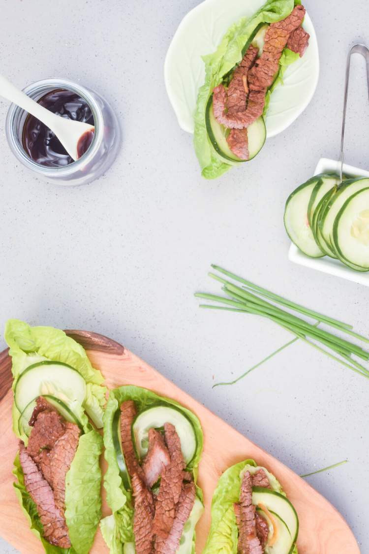 Beef lettuce wraps with korean sauce in lettuce with cucumbers and green onions.