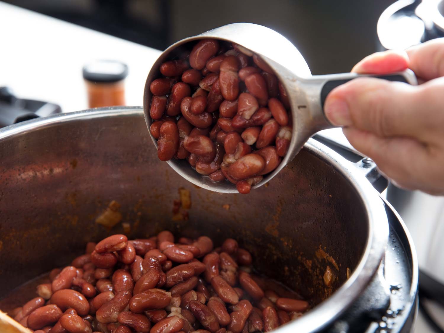 Adding cooked beans to a pot of pressure-cooker chili