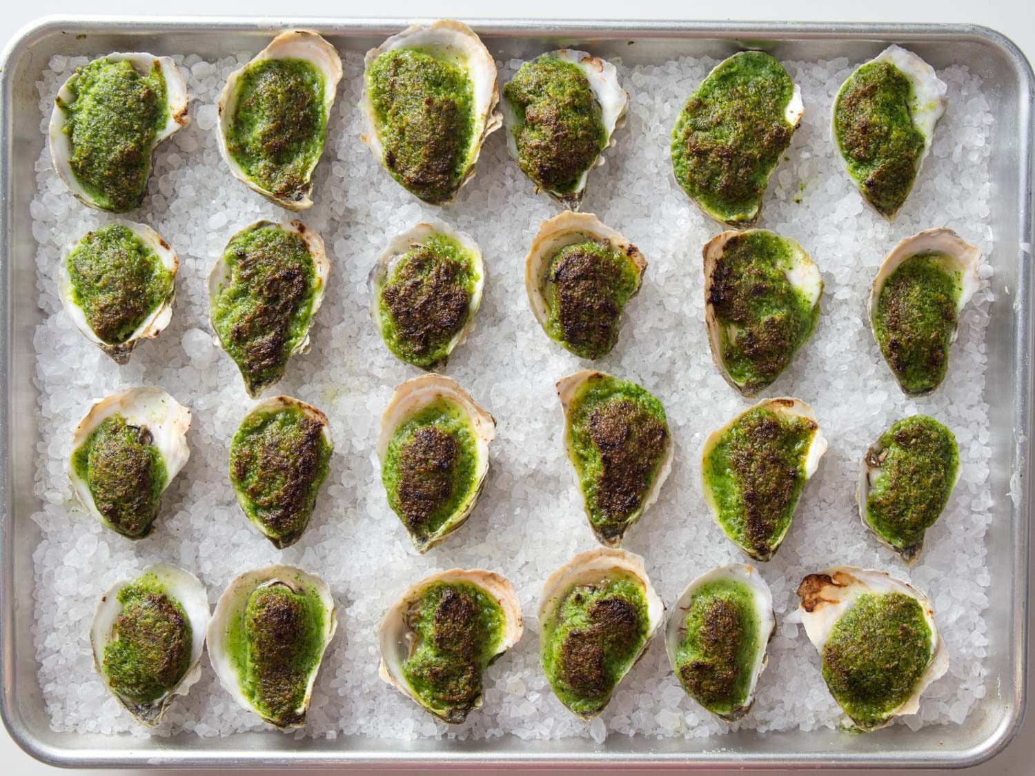 Overhead shot of baking sheet full of oysters Rockefeller.