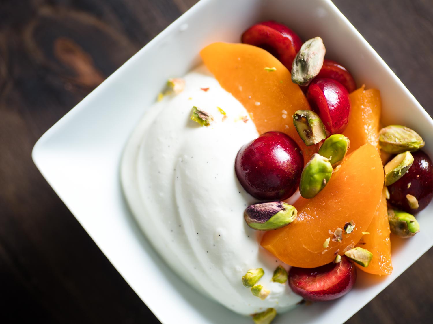 Whipped Greek yogurt with pistachios, cherries, and apricots in a white dish
