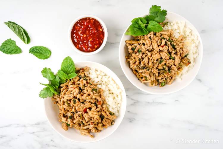Thai larb with ground chicken in two bowls with fresh mint and basil.