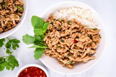 Thai Chicken Larb Thai Chicken Larb with fresh mint and basil in a white bowl with cauliflower rice.