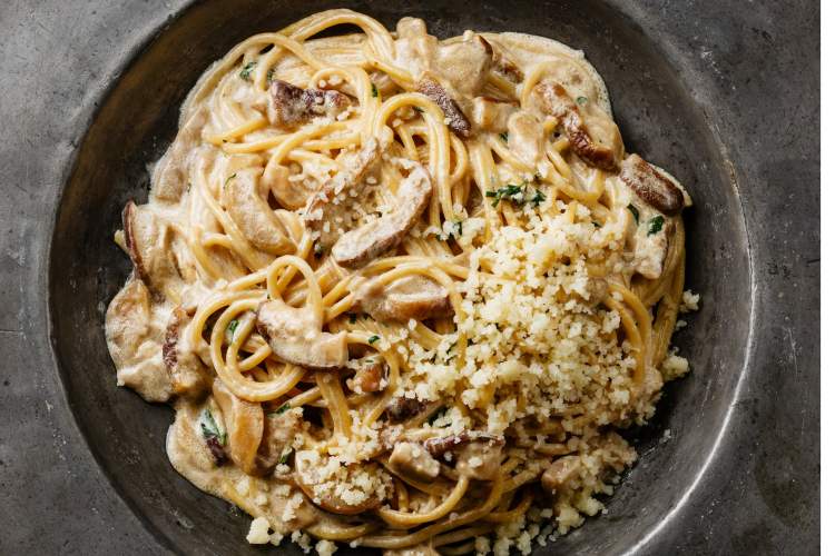 Mushroom pasta with Parmesan cheese in a gray bowl.