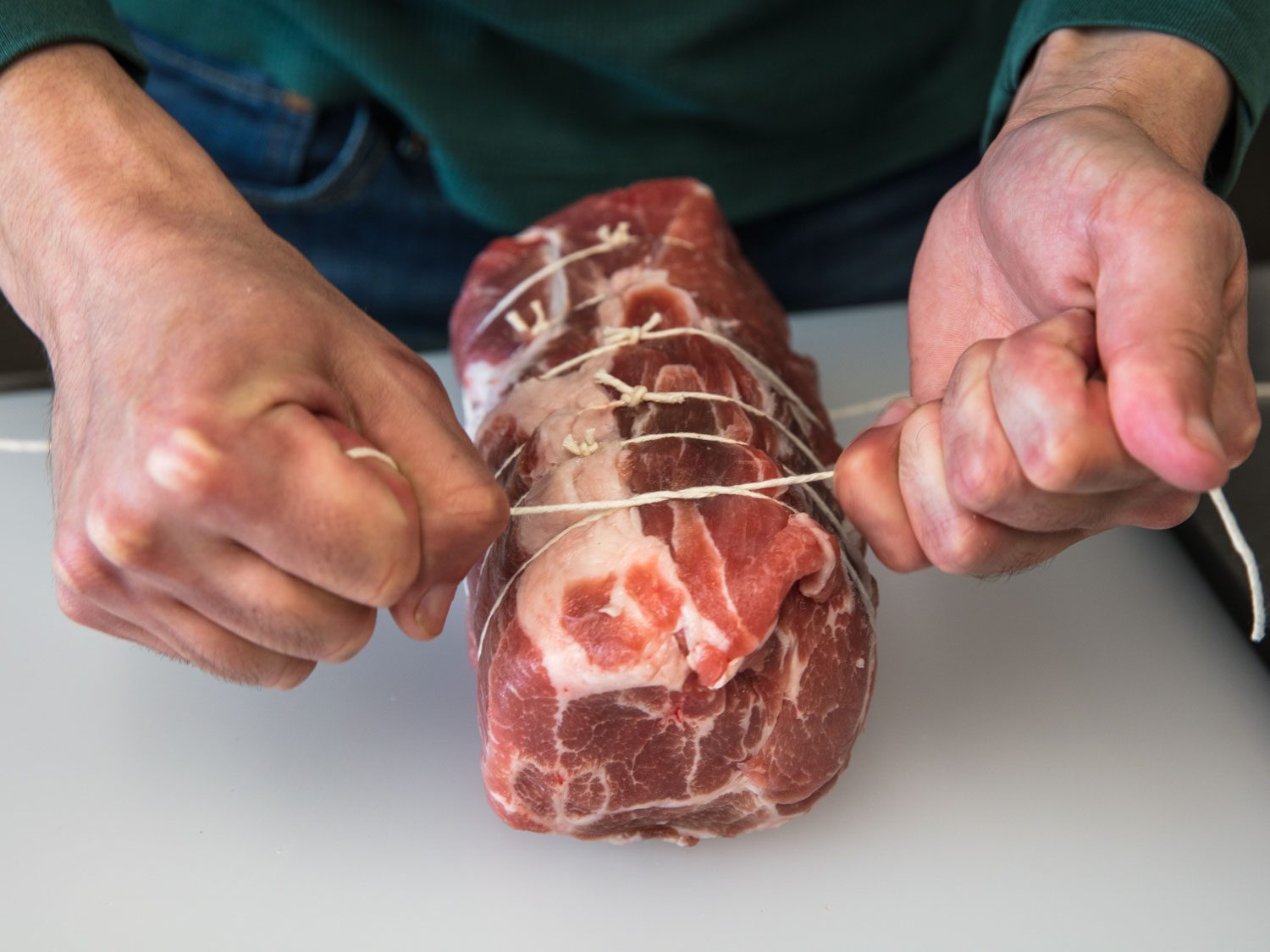 Pork roast being tied with twine at 1/2-inch intervals