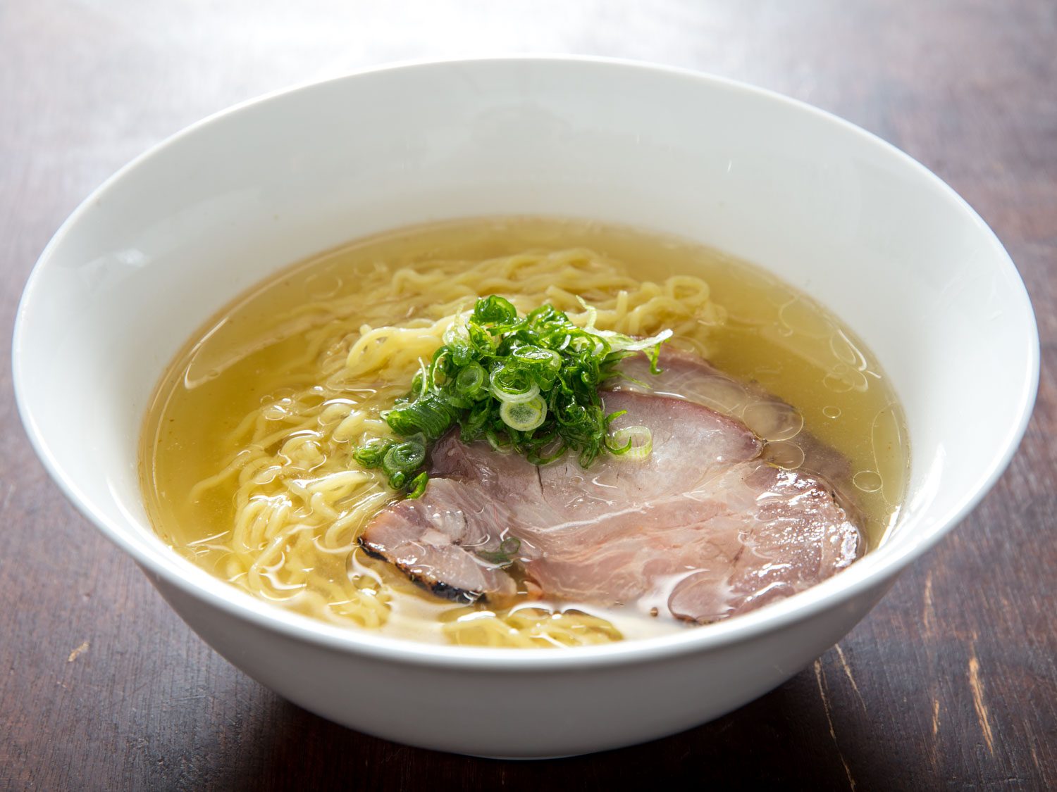 Side view of bowl of shio ramen topped with rolled shoulder chashu