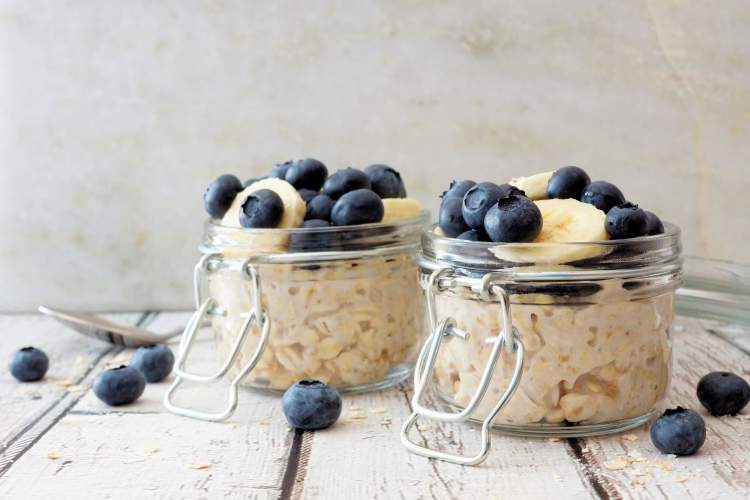 Overnight oatmeal with blueberries, oats, and milk in two jars.