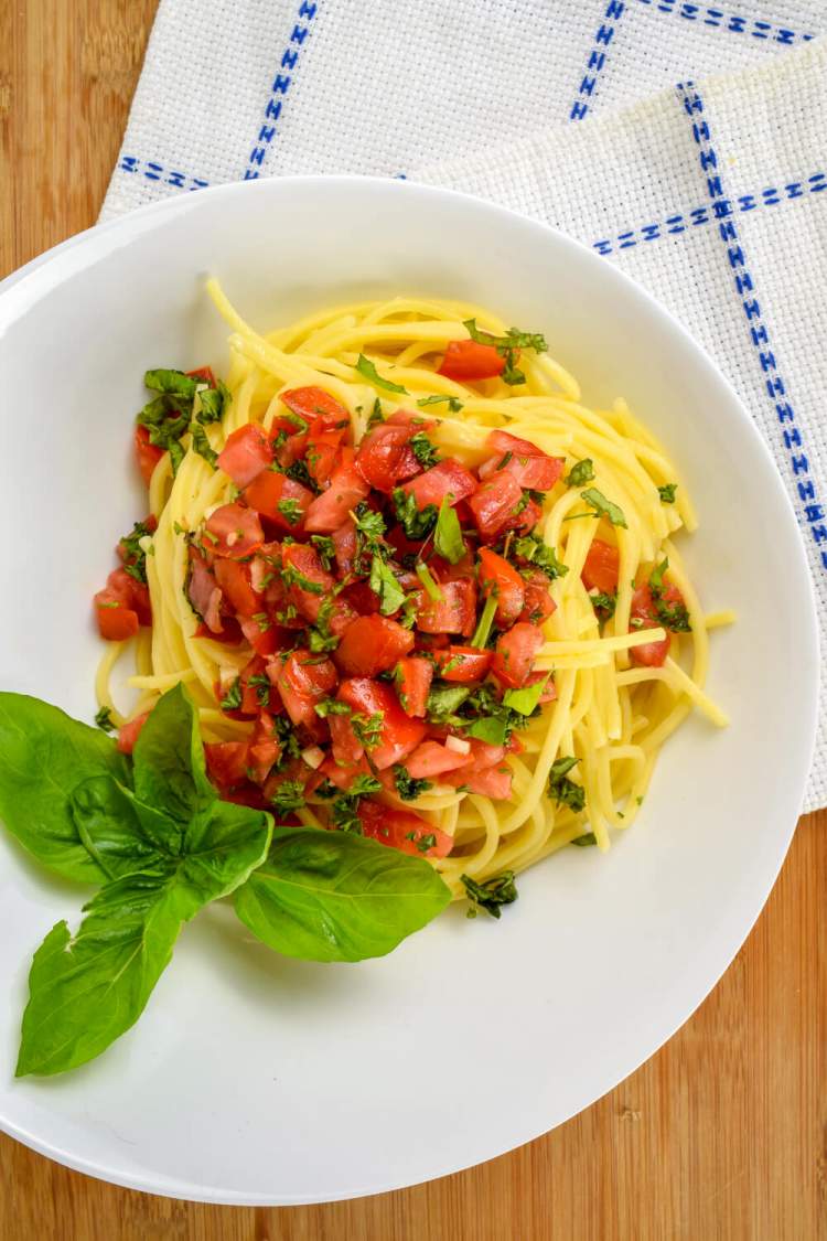 Fresh tomato sauce on a bed of spaghetti with basil.