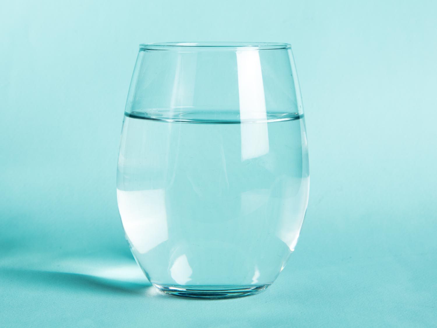 A glass of water against an aqua background
