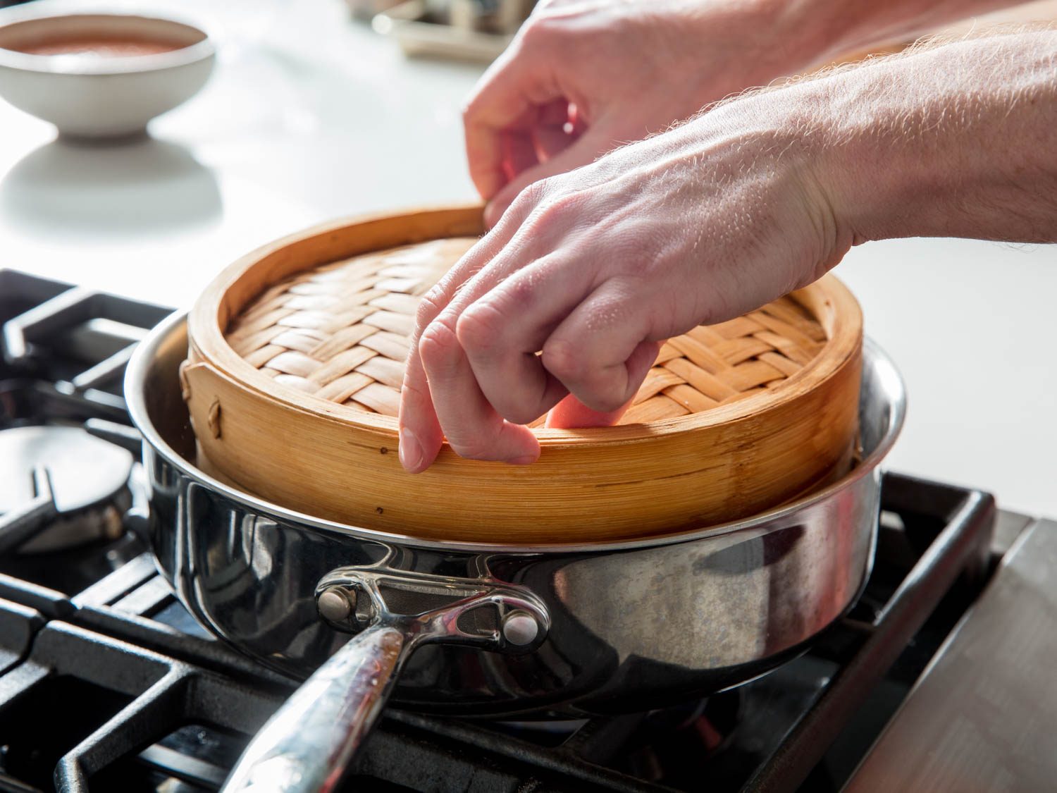 Setting steamer basket inside steaming vessel.