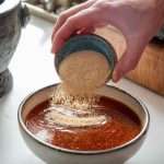 Adding toasted rice powder to dried chili dipping sauce.