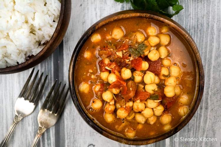 Easy chana masala with white rice in a wooden bowl.