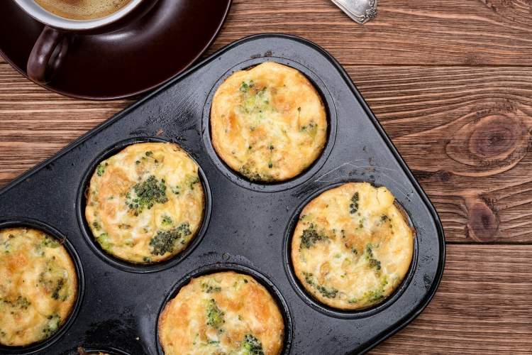 Broccoli cheddar egg muffins in a muffin tin with coffee on the side.