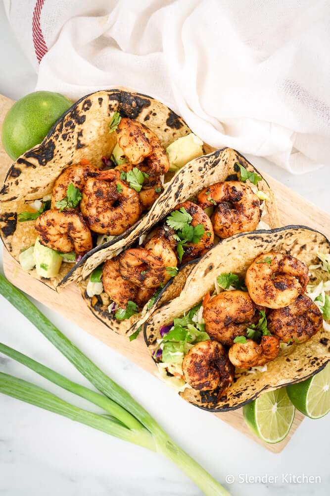 Shrimp Tacos with avocado cilantro slaw on corn tortillas with lime.