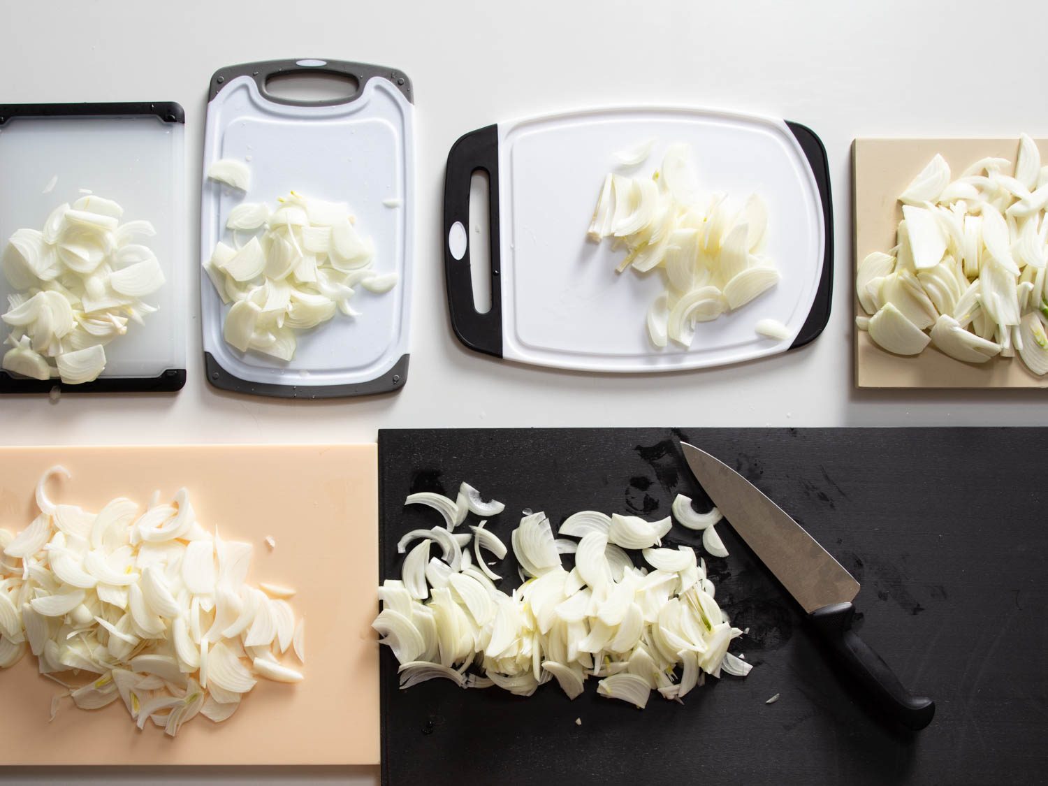 Chopping onions on several plastic cutting boards to compare their performance for our review.