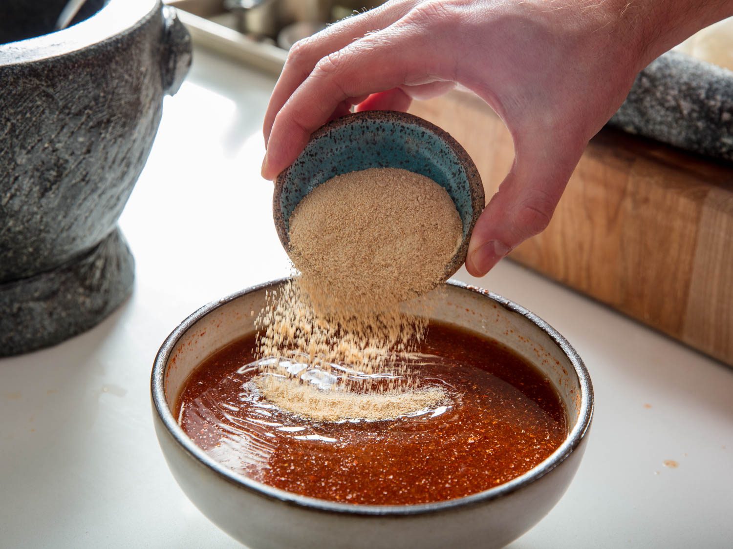 Adding toasted rice powder to dried chili dipping sauce.