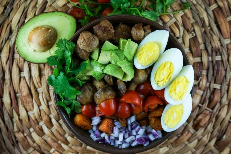 Whole30 breakfast salad with avocado, squash, sausage, eggs, onions, and lettuce.