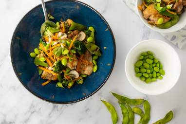 Soy chicken with vegetables including edamame, broccoli, carrots, and onions in a dish.