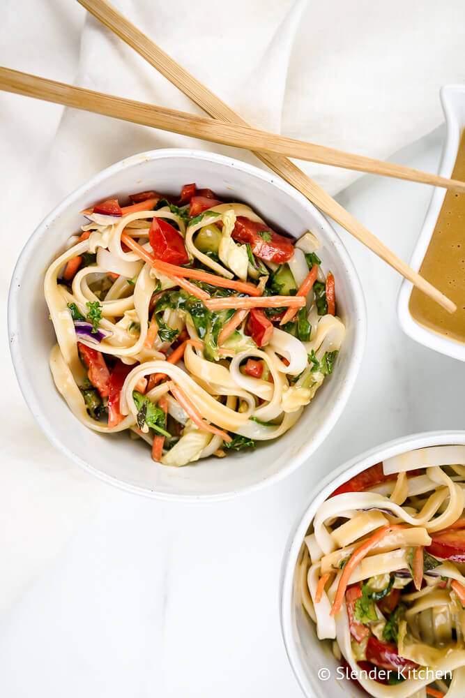 Cold Asian Noodle Salad with almond dressing and vegetables in a bowl with chopsticks.