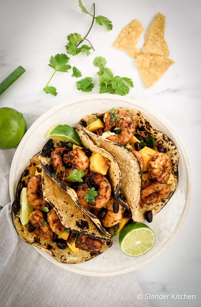 Tacos with spicy shrimp and mango salsa with cilantro and lime juice.