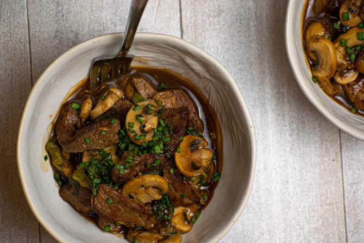 Stir Fry with beef, bok choy, and mushrooms in a bowl with sauce.