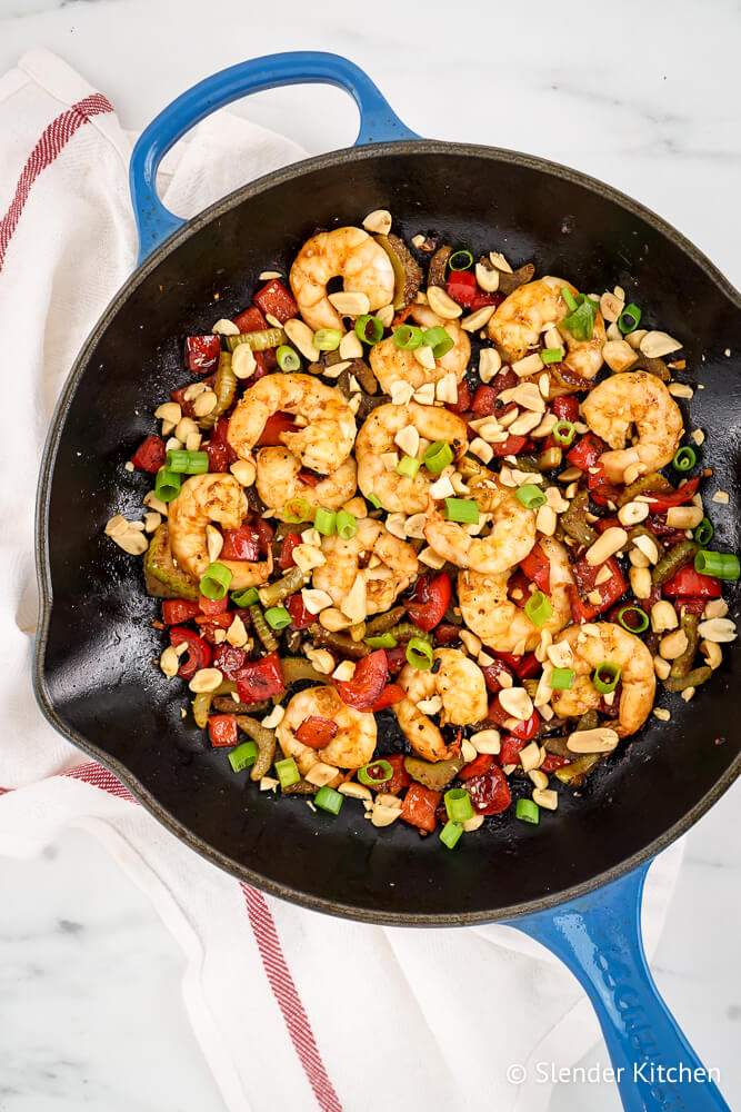 Healthy Kung Pao Shrimp in a skillet with red pepper, celery, and peanuts.