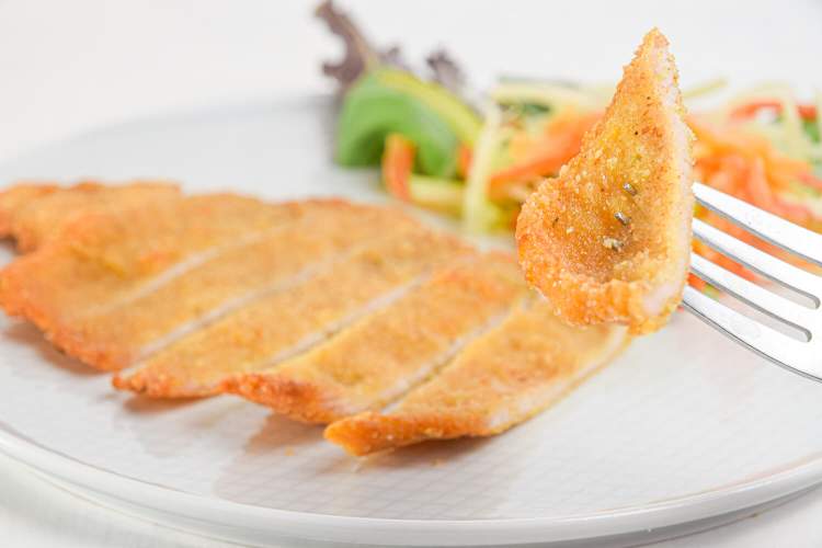 Honey mustard pork chops with a crispy coating on a white plate with two forks.