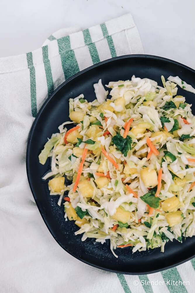 Pineapple coleslaw with coconut dressing, cilantro, carrots, cabbage, and diced pineapple in a bowl.