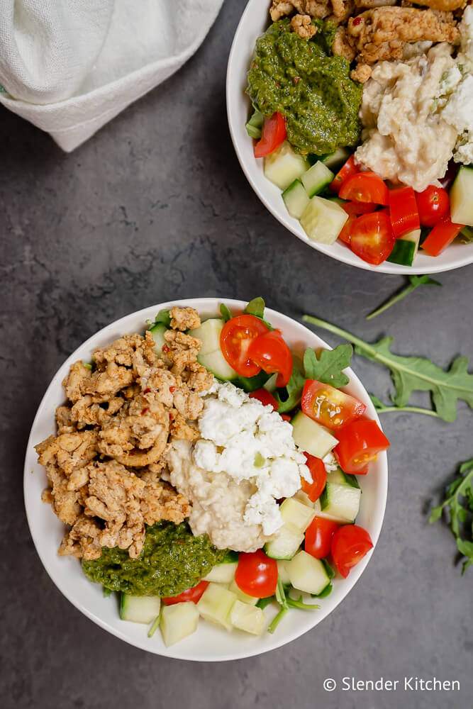 Chicken kofta made with ground chicken and spices in a bowl with vegetables and hummus.