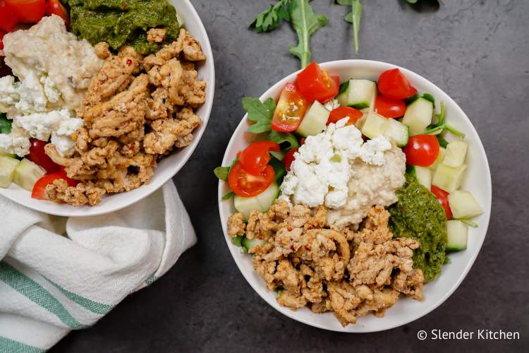 Kofta chicken bowls with baba ganoush, hummus, zhoug, tomatoes, and cucumbers in a bowl.