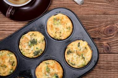 Broccoli Cheddar Egg Muffins in a metal muffin tin with coffee on the side.