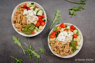 Chicken kofta bowls with arugula, tomatoes, cucumbers, hummus, and feta cheese in a bowl.