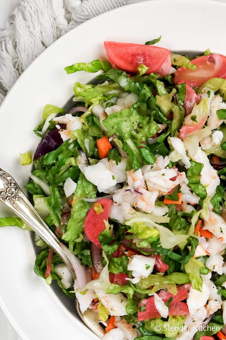 Shrimp salad with chopped shrimp, avocado, radishes, herbs, and Romaine lettuce in a bowl with lemon dressing.