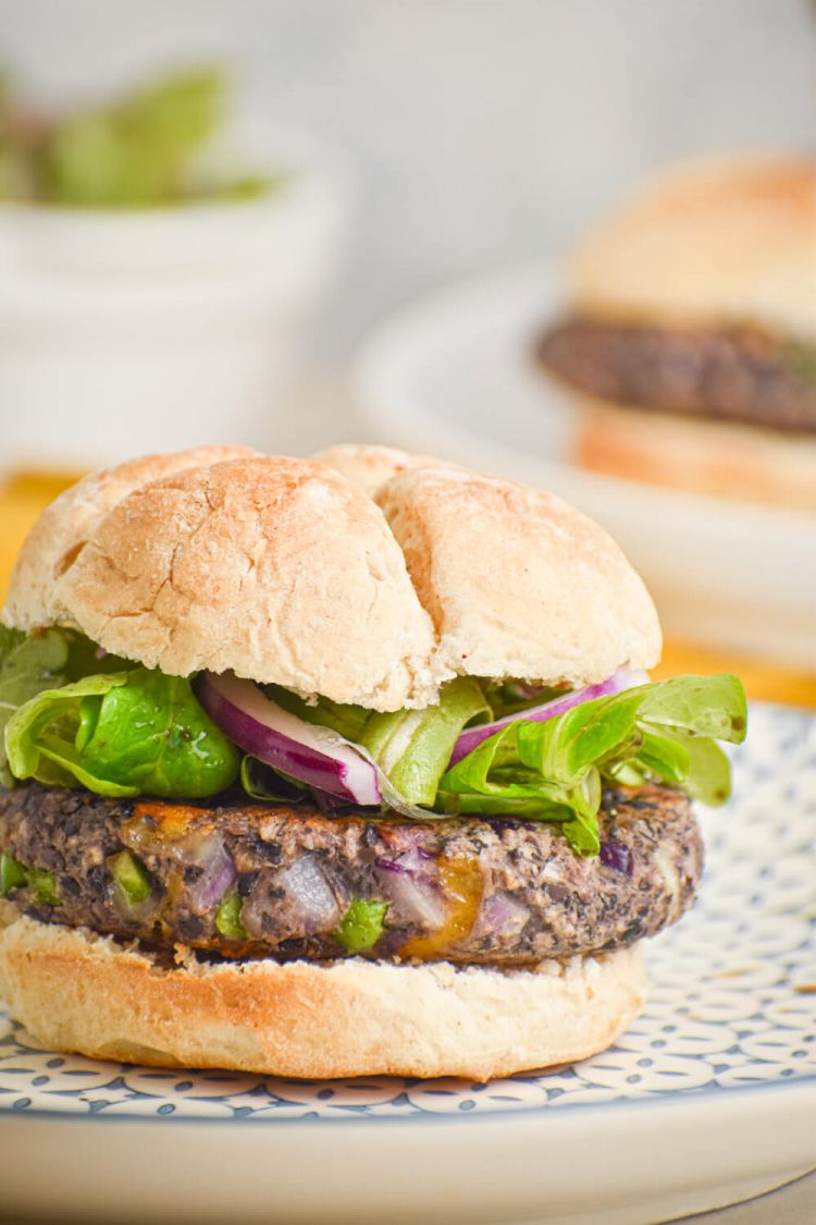 Black bean burgers with jalapenos and cheddar cheese on a bun with lettuce and onions.
