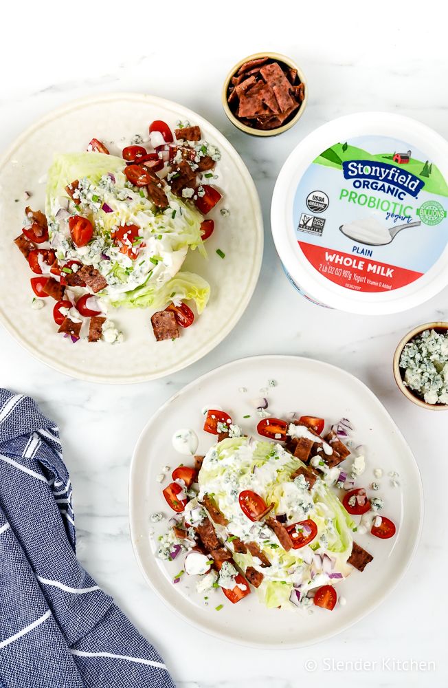 Classic wedge salad with creamy yogurt blue cheese dressing, crispy bacon, tomatoes, and red onions.